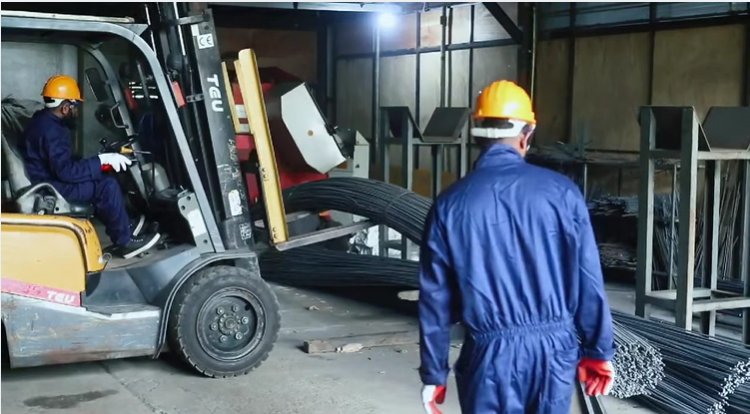 Forklift moving coils of reinforcement steel past stacked deformed bars at the K A Piyasena & Sons factory
